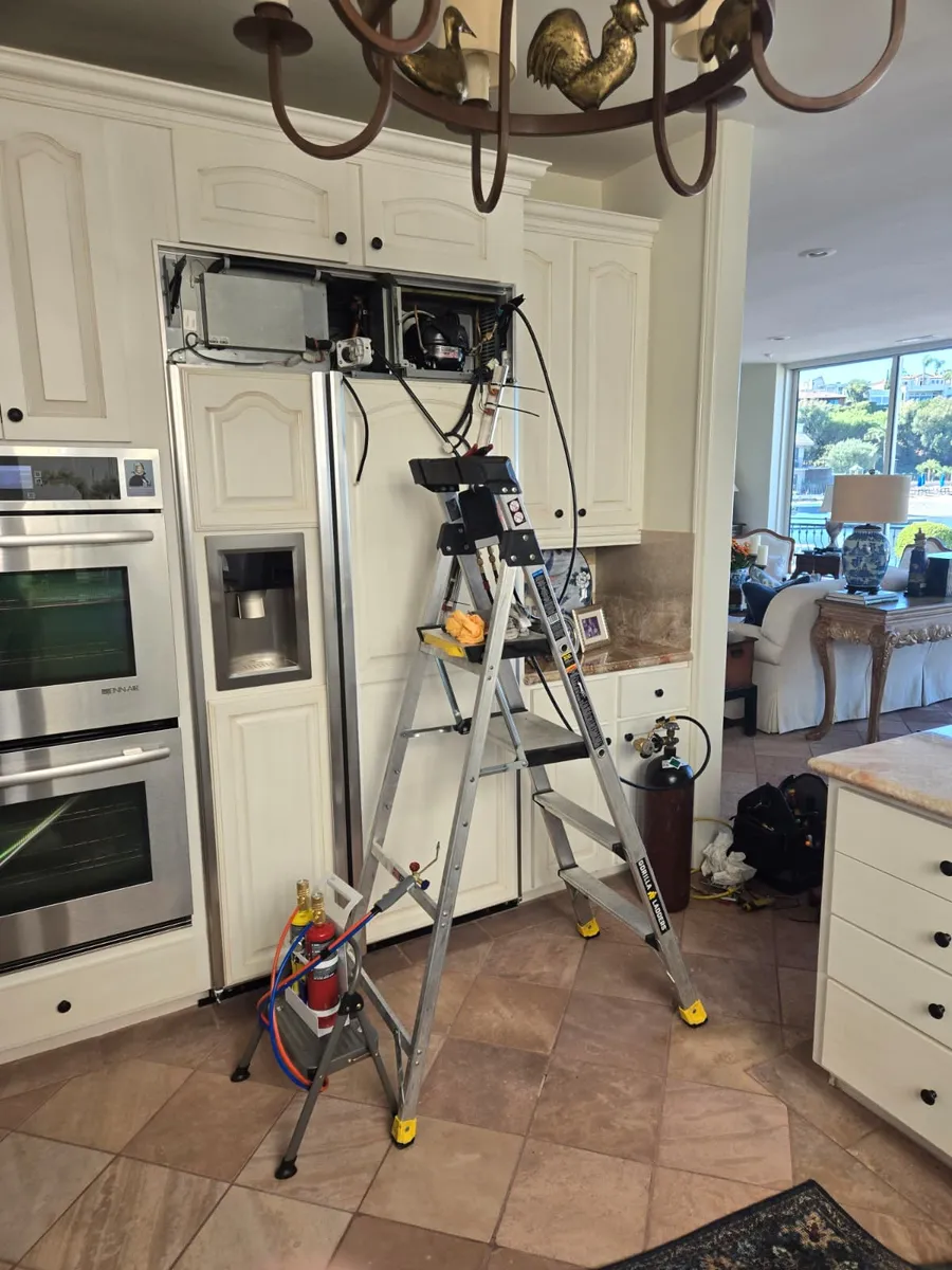 Epic Star technician servicing the top compressor of a built-in side-by-side refrigerator in a Beverly Hills kitchen